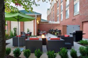 un patio con mesas, sillas y una sombrilla en Hilton Garden Inn Atlanta North/Johns Creek, en Johns Creek