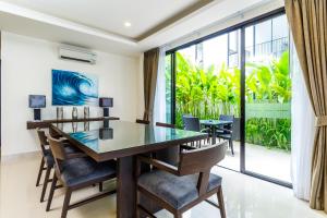 a dining room with a table and chairs and a large window at Laguna Park Villa with rooftop pool by Lofty in Bang Tao Beach