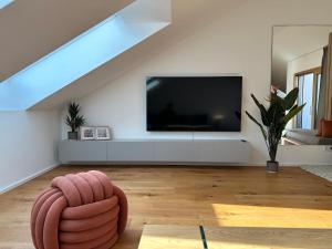 ein Wohnzimmer mit einem Flachbild-TV und einem Sofa in der Unterkunft Direkt am Rathausplatz, Dachterrasse mit Blick auf Perlachturm in Augsburg