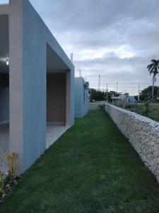 a building with a grass yard next to a wall at Cabrera Family Villa in Cabrera