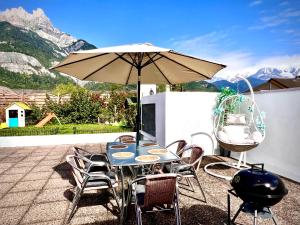 a table and chairs with an umbrella on a patio at Rooftop 1 - Jacuzzi privé au pied du Monte-blanco in Sallanches