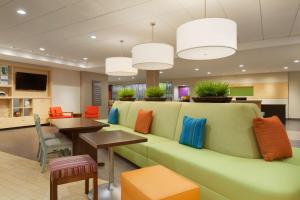 a waiting room with a green couch and a table at Home2 Suites By Hilton El Paso Airport in El Paso