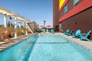 a swimming pool with blue chairs and a building at Home2 Suites By Hilton El Paso Airport in El Paso