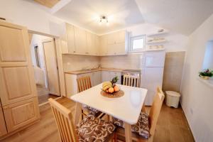een kleine keuken met een witte tafel en stoelen bij Apartmani Šarović Tara 3 in Rača
