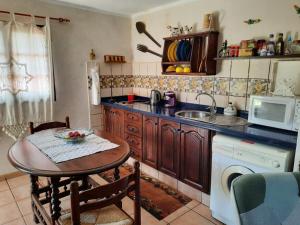 een keuken met een tafel, een wastafel en een magnetron bij Casa Rural Sanjora in Valverde