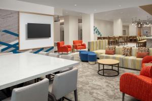 una sala de espera con mesas, sillas y TV en Hilton Garden Inn Orlando Downtown en Orlando