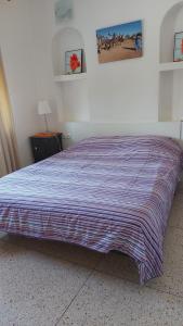 a bed in a bedroom with a striped blanket on it at Club Evasion in Tamelalt