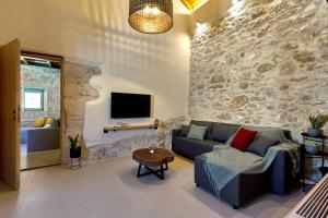 sala de estar con sofá azul y pared de piedra en Vin Dimora Suites, en Archanes