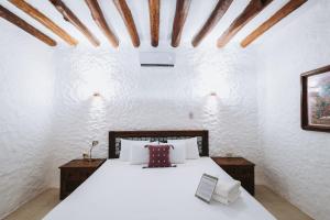a bedroom with a large white bed with white walls at Hotel Casa Barbara Holbox in Holbox Island