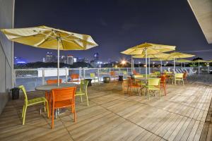 eine Terrasse mit Tischen, Stühlen und Sonnenschirmen in der Nacht in der Unterkunft Home2 Suites by Hilton Dallas Downtown at Baylor Scott & White in Dallas