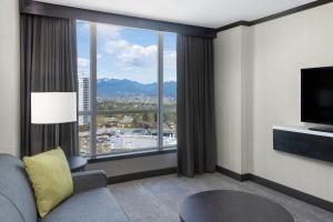ein Wohnzimmer mit einem großen Fenster in einem Hotelzimmer in der Unterkunft Hilton Vancouver Metrotown in Burnaby
