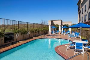 a swimming pool with chairs and tables and umbrellas at Hampton Inn & Suites Paso Robles in Paso Robles