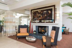a living room with two chairs and a fireplace at Hilton Garden Inn West Lafayette Wabash Landing in Lafayette