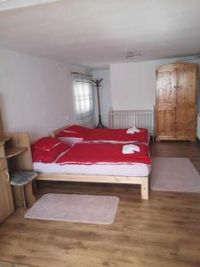 1 dormitorio con 1 cama grande con almohadas rojas en Agapé Vendégház, en Cserépfalu