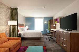 a hotel room with a bed and a flat screen tv at Home2 Suites By Hilton Silver Spring in Silver Spring