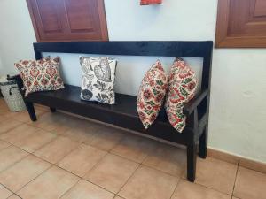 a black bench with four pillows on it at Casa Rural Sanjora in Valverde