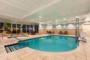 a pool in a hotel with tables and chairs at Hilton Garden Inn Dulles North in Ashburn
