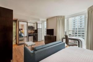 um quarto com uma cama, um sofá e uma televisão em Homewood Suites Midtown Manhattan Times Square South em Nova York