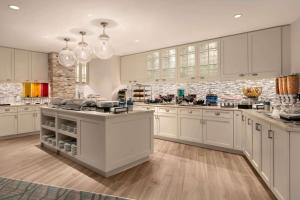 ワシントンにあるHomewood Suites by Hilton Washington DC Convention Centerの白いキャビネットと大きな島のある広いキッチンが備わります。