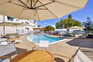 uma piscina com mesas, cadeiras e guarda-sóis em Homewood Suites by Hilton - Oakland Waterfront em Oakland