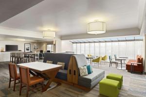 a living room with a couch and a table and chairs at Hampton Inn Portland Airport in Portland