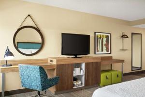 a bedroom with a desk with a television and a chair at Hampton Inn Portland Airport in Portland