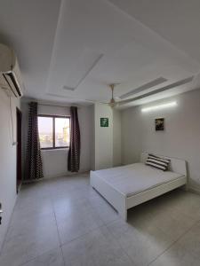 um quarto branco com uma cama e uma janela em Three Bed Attached Bath Netflix Wifi Smart TV Parking WFH Desk Near Airport em Islamabad