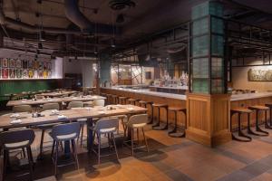 伯明翰Hilton Birmingham Downtown at UAB的有木桌椅和酒吧的餐厅