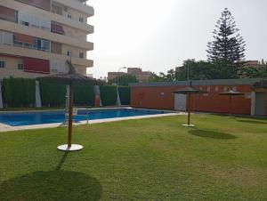 two umbrellas sitting in the grass next to a pool at Apartamento Vallehermoso in El Puerto de Santa María