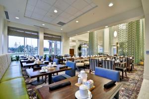 a restaurant with wooden tables and blue chairs at Hilton Garden Inn Detroit Troy in Troy