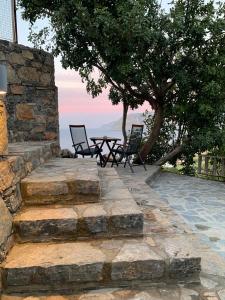 a patio with two chairs and a table on a stone wall at Petra Nova Villas in Mochlos