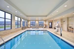 a pool in a hotel with a large room with windows at Hampton Inn Livonia Detroit in Livonia