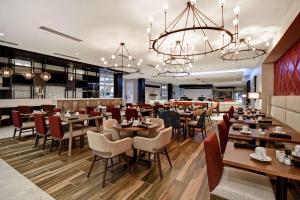 a restaurant with wooden tables and chairs and a chandelier at Hilton Garden Inn Lansing West in Lansing