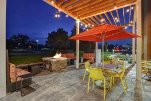 eine Terrasse mit einem Tisch, Stühlen und einem Sonnenschirm in der Unterkunft Home2 Suites by Hilton Troy in Troy