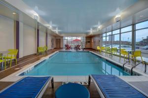 een groot zwembad met gele stoelen en tafels bij Home2 Suites by Hilton Troy in Troy