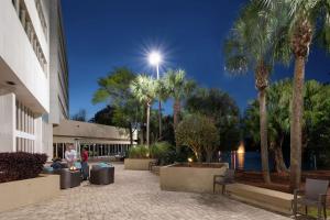 un uomo in piedi fuori da un edificio con palme di DoubleTree by Hilton Hotel Jacksonville Airport a Jacksonville