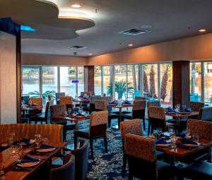 a dining room with tables and chairs and windows at DoubleTree by Hilton Hotel Jacksonville Airport in Jacksonville