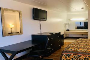 a bedroom with a desk and a bed and a mirror at Economy Inn by OYO Holland in Holland