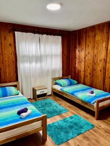 two beds in a room with wooden walls and blue rugs at Kuća za odmor Bilić 