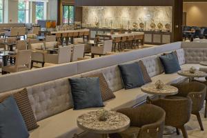 un restaurante con mesas y sillas y un bar en Hilton Raleigh North Hills en Raleigh