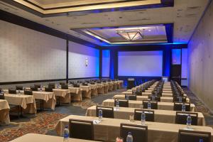 una sala conferenze con tavoli, sedie e schermo di Hilton Raleigh North Hills a Raleigh