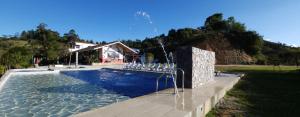 a swimming pool with white chairs next to a house at HOSTERÍA BRISAS DEL RÍO in Marinilla