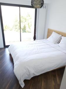 een groot wit bed in een slaapkamer met een groot raam bij Maison entourée d animaux en pleine campagne in Lasseube