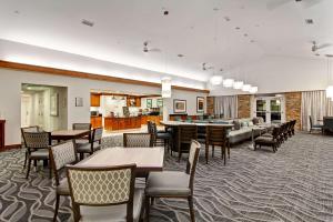 a restaurant with tables and chairs and a living room at Homewood Suites by Hilton Bentonville-Rogers in Rogers