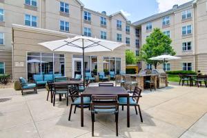 a patio with tables and chairs and an umbrella at Homewood Suites by Hilton Bentonville-Rogers in Rogers