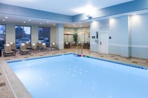 a large pool in a hotel room with chairs and tables at Hampton Inn & Suites Chicago North Shore in Skokie