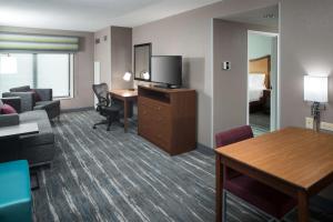 Habitación de hotel con sofá y escritorio con TV. en Hampton Inn & Suites Chicago North Shore, en Skokie