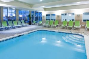 una piscina en una habitación de hotel con sillas y mesas en Hilton Garden Inn Cincinnati/Mason en Mason