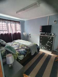 Schlafzimmer mit einem Bett und einem Flachbild-TV in der Unterkunft KUSVAALBOS SELFSORG WOONSTEL in De Kelders