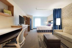 Home2 Suites by Hilton Milwaukee Airport في ميلووكي: غرفة في الفندق مع سرير ومكتب مع أريكة